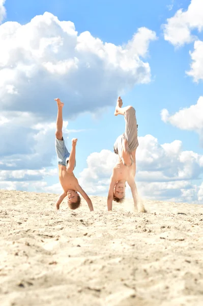 Dos chicos de pie sobre sus manos en una arena —  Fotos de Stock