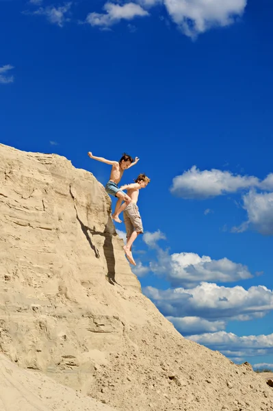 Rapazes saltando ffom uma colina de areia — Fotografia de Stock