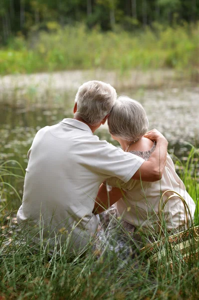 Oude paar zitten in de buurt van lake — Stockfoto