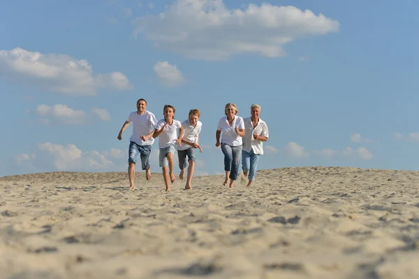 Lycklig familj kör på en strand — Stockfoto
