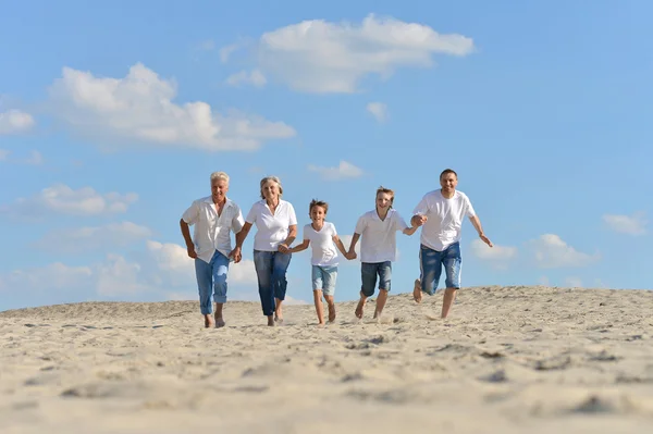 Familia feliz corriendo en una playa — Foto de Stock