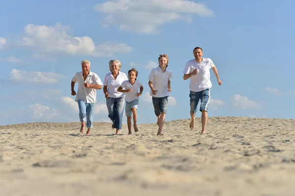 Família feliz correndo em uma praia — Fotografia de Stock