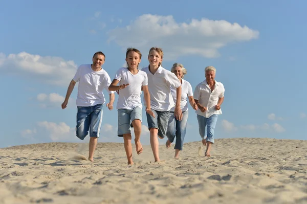 Familia feliz corriendo en una playa — Foto de Stock