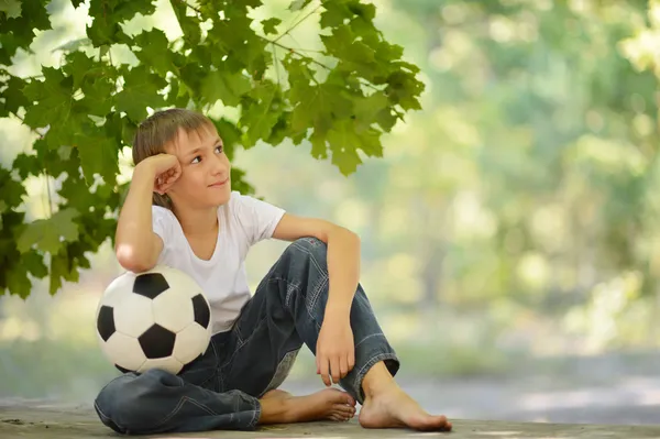 Junge sitzt mit einem Fußballball — Stockfoto