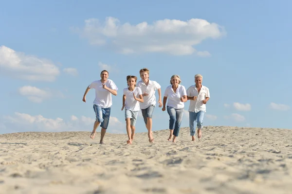 Familia feliz corriendo en una playa — Foto de Stock