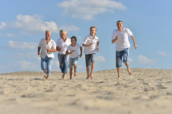 Família feliz correndo em uma praia — Fotografia de Stock