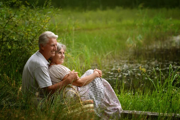 Velho e mulher sentados em uma grama — Fotografia de Stock