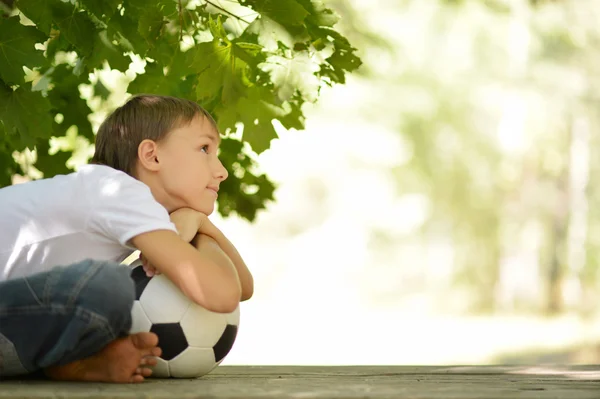 Garçon est assis avec un ballon de football — Photo