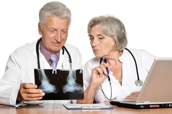 Médicos ancianos con una computadora portátil mirando rayos X en un blanco —  Fotos de Stock