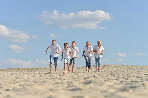 Família feliz correndo em uma praia — Fotografia de Stock