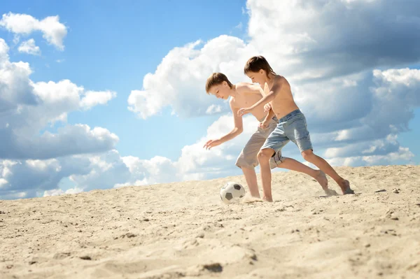 Två pojkar som spelar fotboll på en sand — Stockfoto