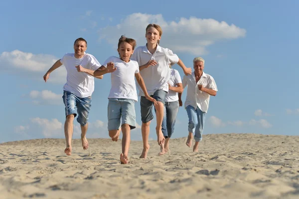 Família feliz correndo em uma praia — Fotografia de Stock