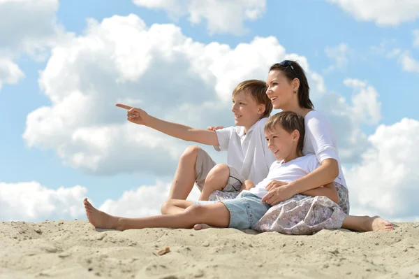 Família feliz sentada em uma areia — Fotografia de Stock