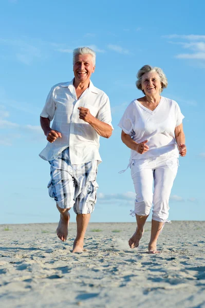 Casal velho correndo em uma praia — Fotografia de Stock