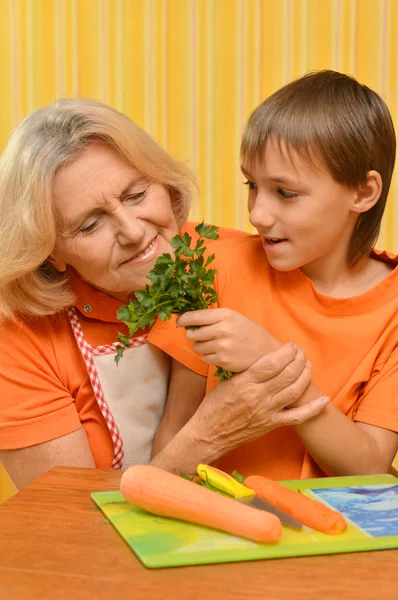 Šťastný starší žena a chlapec v oranžové barvě v kuchyni — Stock fotografie