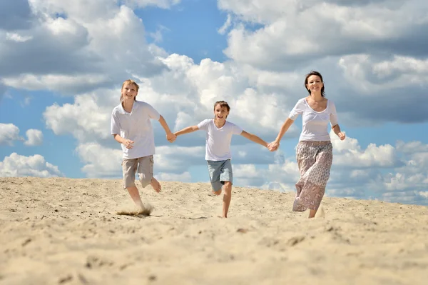 Mãe e filhos correm em uma praia — Fotografia de Stock