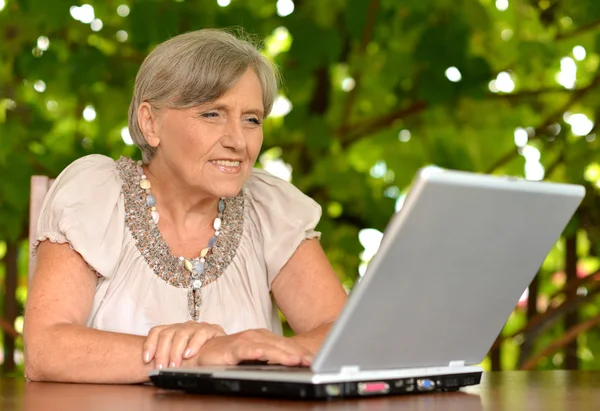 Older woman with computer outdoors — Stock Photo, Image