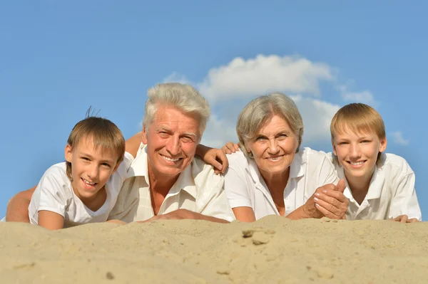 Barn på en strand med mor-och farföräldrar — Stockfoto