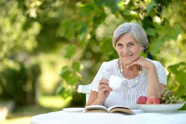 Senior dame op een tabel buitenshuis — Stockfoto