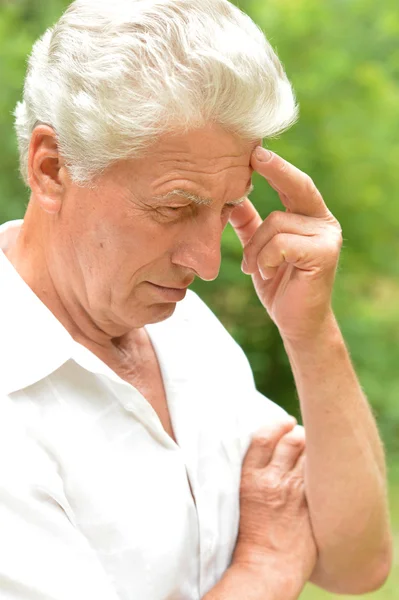 Pensive elderly man out for a walk in the park in summer — Stock Photo, Image