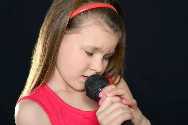 Chica cantando sobre un fondo negro — Foto de Stock