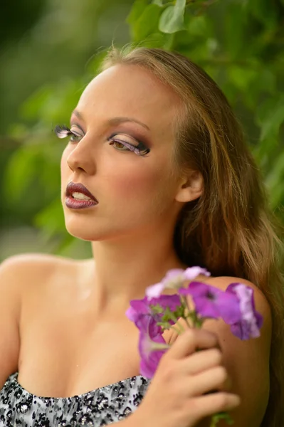 Flicka med blommor och konstnärlig makeup — Stockfoto