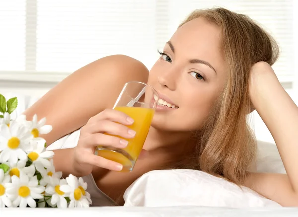 Menina beber suco na cama — Fotografia de Stock