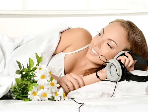 Menina na cama com flores ouvindo música — Fotografia de Stock