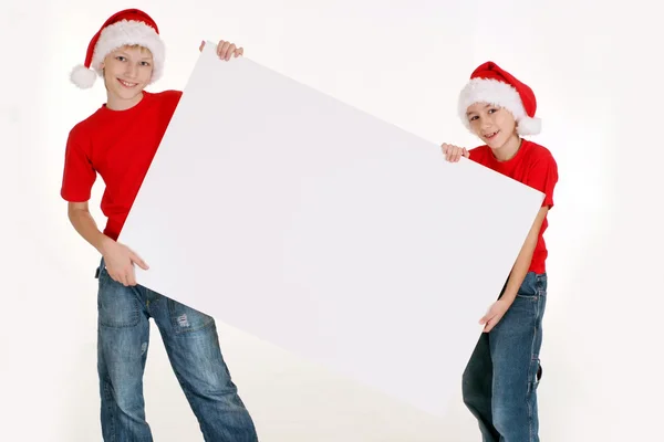 Kids in santa hats with board — Stock Photo, Image