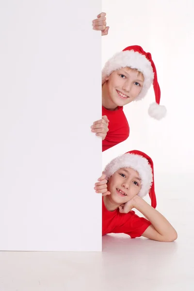 Kinder in Weihnachtsmützen mit Brett — Stockfoto