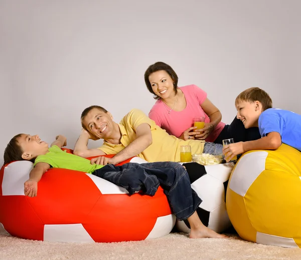Familie schaut fern, trinkt und isst — Stockfoto