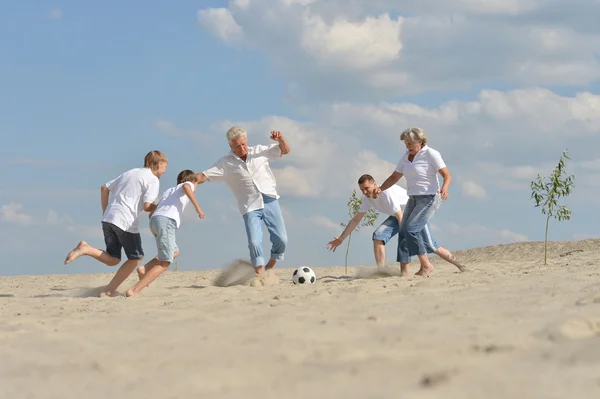 Familj spelar fotboll på stranden — Stockfoto