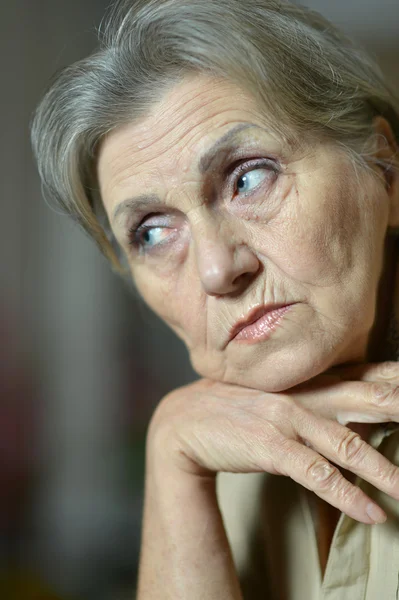 Sad elderly woman on a gray background — Stock Photo, Image