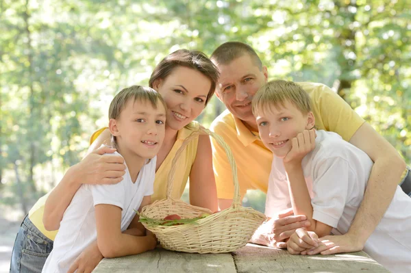 Família feliz com uma cesta de frutas — Fotografia de Stock