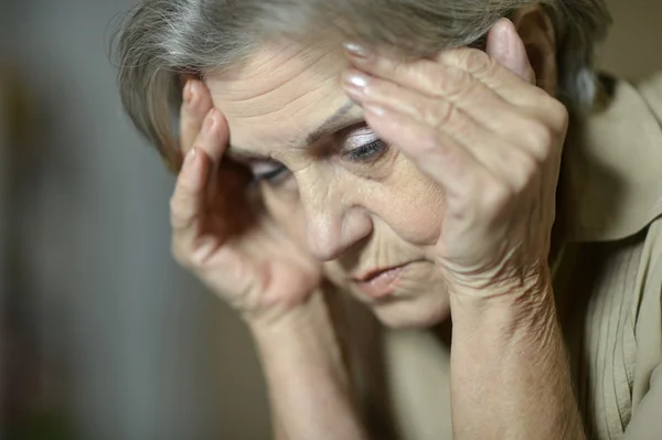 Triest oudere vrouw op een grijze achtergrond — Stockfoto