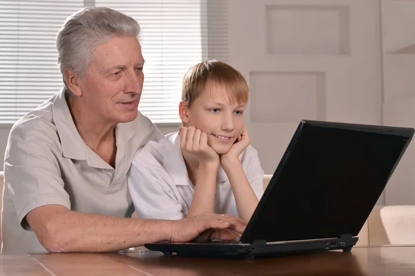 Pojken och hans farfar med en bärbar dator — Stockfoto