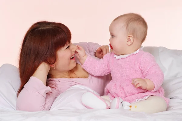 Egy boldog mama kaukázusi lánya ágyban fekve — Stock Fotó