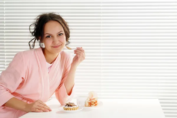 Una hermosa chica caucásica sentada a la mesa con un pastel — Foto de Stock
