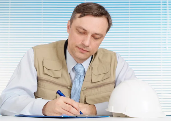 Escrevendo homem trabalhando no capacete de construção — Fotografia de Stock