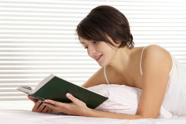 Mulher lendo em uma cama — Fotografia de Stock