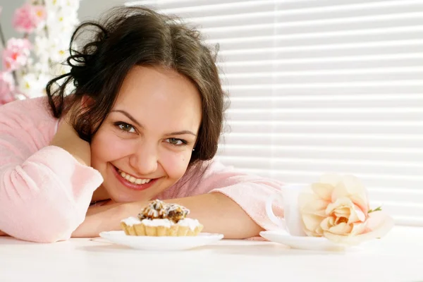 Beautiful happy woman is and looks at a cake — Stock Photo, Image