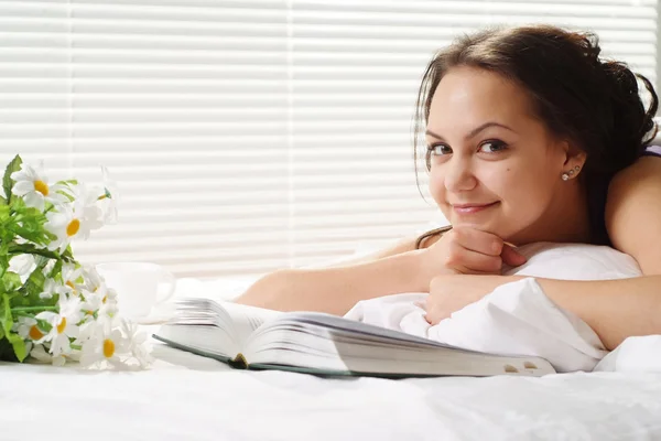 Mulher muito caucasiana deitada em uma cama de livro — Fotografia de Stock