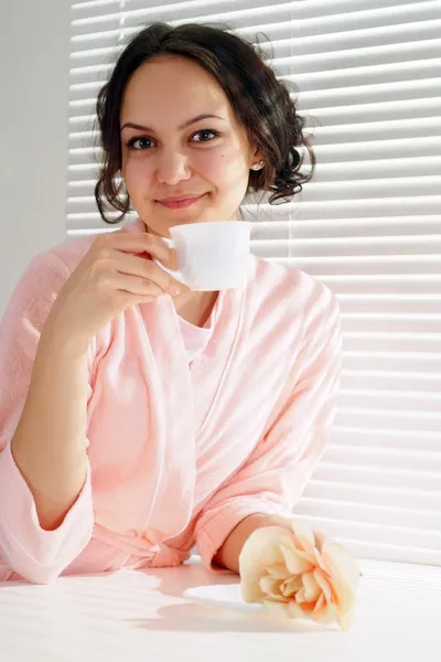 Una hermosa chica caucásica sentada a la mesa con una taza — Foto de Stock