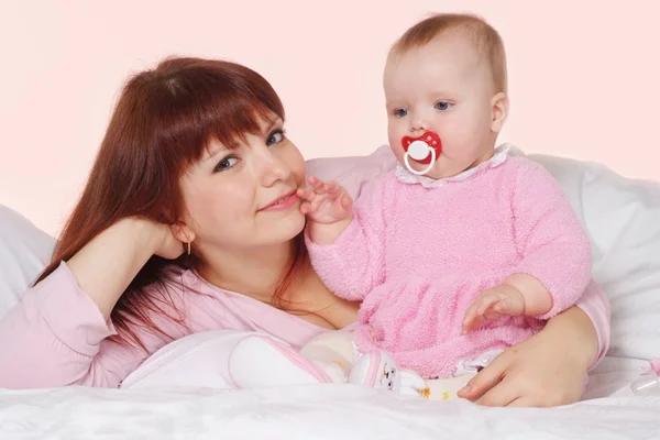 A pretty Caucasian mama with her daughter lying in bed — Stock Photo, Image