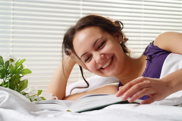 Pretty Caucasian woman lying in a bed of book — Stock Photo, Image