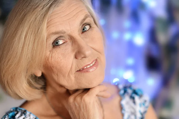 Mulher mais velha alegre em um fundo azul — Fotografia de Stock