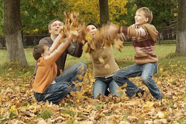 Vacker familj kastar höstlöv — Stockfoto