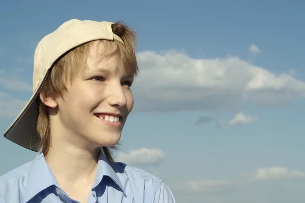 A beautiful caucasian boy in a cap sits — Stock Photo, Image