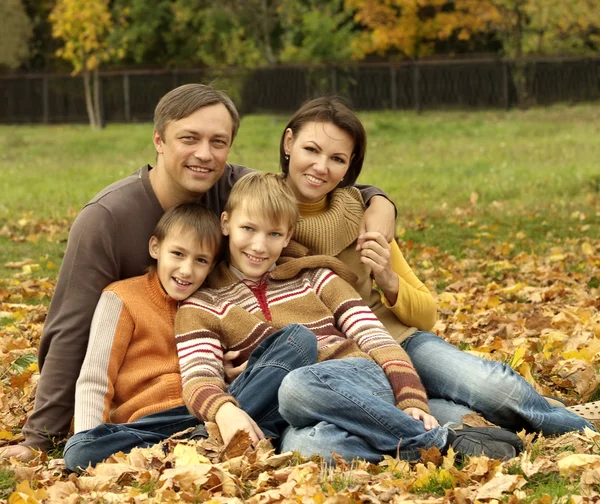 Familjen sitter i en höst park — Stockfoto