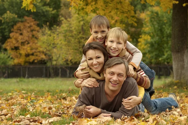 Leuke familie liggen in de herfst park — Stockfoto